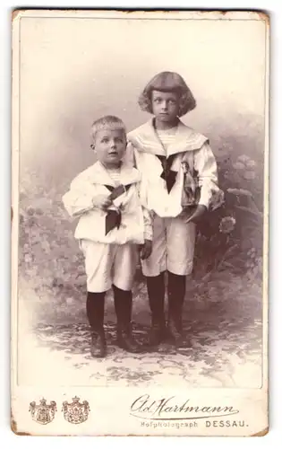 Fotografie Ad. Hartmann, Dessau, zwei niedliche Kleinkinder in Matrosenanzügen mit Spielzeug Pferd und Flagge