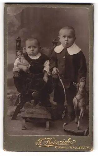 Fotografie F. Heinrich, Torgau, zwei Kinder Hilde & Herbert mit Schaukelpferd und Puppe im Arm