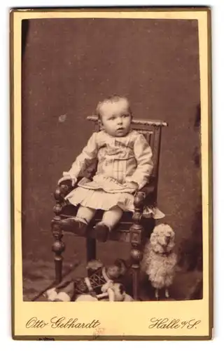 Fotografie Otto Gebhardt, Halle / Saale, Kleinkind im Kleid mit Spilezeug unterm Stuhl