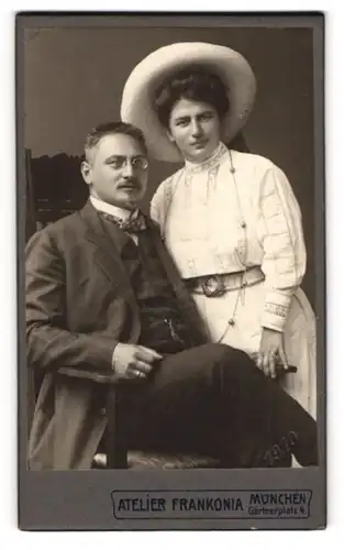 Fotografie Atelier Frankonia, München, Gärtnerplatz 4, Herr im eleganten Dreiteiler und Dame mit Strohhut und Gürtel