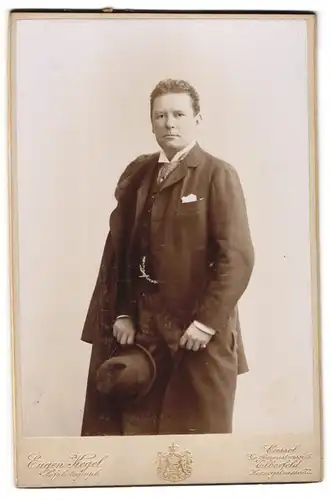 Fotografie Eugen Kegel, Cassel, junger Mann im Anzug mit Hut und Mantel über der Schulter, 1895