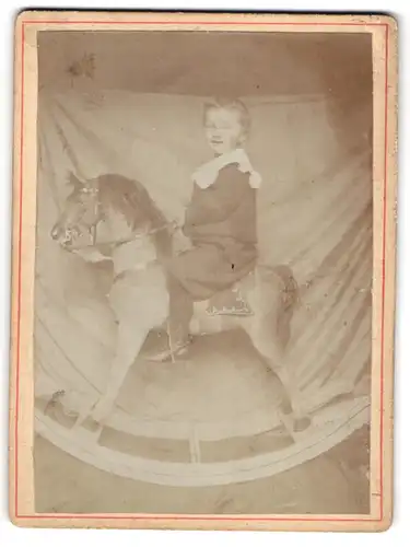 Fotografie unbekannter Fotograf und Ort, kleines Kind auf einem grossen Schaukelpferd