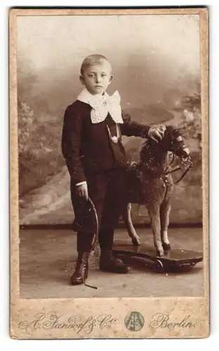 Fotografie A. Jandorf & Co., Berlin, junger Knabe mit Schaukelpferd auf Rädern und Peitsche