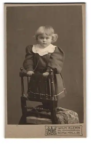 Fotografie Wilh. Klemm, Schw. Hall, süsses blondes Mädchen im Kleid auf einem Stuhl stehend