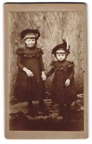 Fotografie unbekannter Fotograf und Ort, zwei kleine Mädchen in dunklen Kleidern mit Baskenmütze