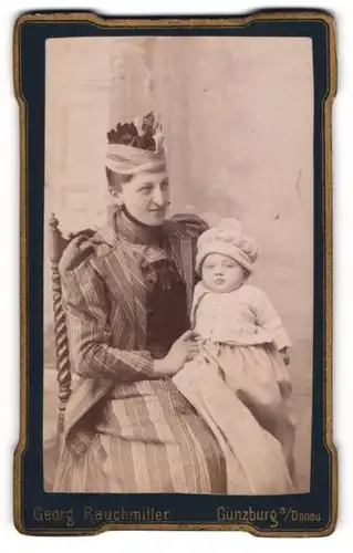 Fotografie Georg Rauchmiller, Günzburg a. D., Mutter im gestreiften Kleid mit ihrem Kind auf dem Schoss, Mutterglück