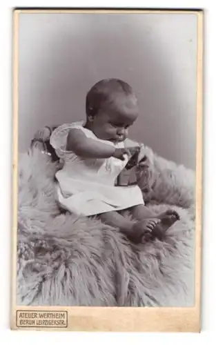 Fotografie Atelier Wertheim, Berlin, Leipzigerstrasse, Spielendes Baby im Strampelkleid auf einem Fell