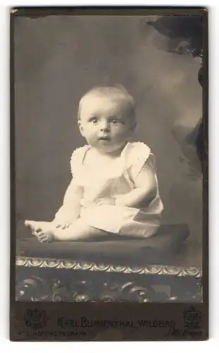 Fotografie Karl Blumenthal, Wildbad, Sitzendes Baby mit aufmerksamem Blick im Strampelkleidchen