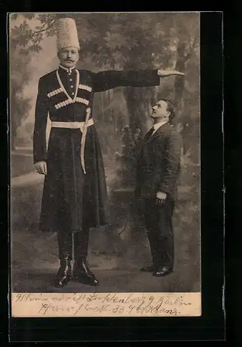 AK Berlin, Riese mit Fellmütze neben kleinem Mann, Abnormitätenschau P. C. Erven