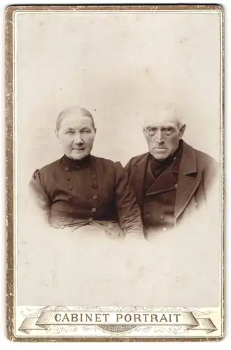 Fotografie Cabinet Portrait, Ort unbekannt, Alte Frau im Oberteil mit Zierknöpfen und bartloser alter Mann im Mantel