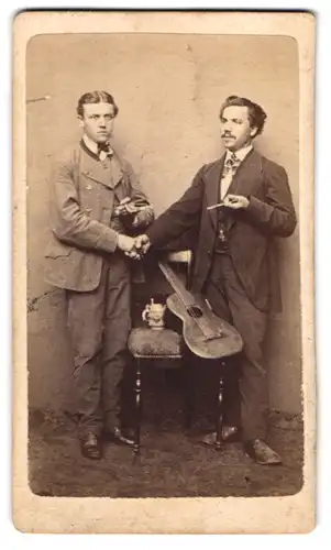 Fotografie A. Bringruber, Hemau, Portrait zwei bayrische Musiker mit Gitarre und Bierkrug auf dem Stuhl