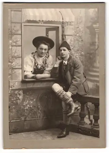 Fotografie Ernst Eberle, Ulm a. D., junges Paar in bayrischer Tracht posieren in einer Studiokulisse, 1908
