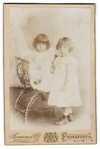 Fotografie Samson & Co., Frankfurt a. M., Zeil 46, Zwei kleine Kinder mit Ponyfrisuren in weissen Sonntagskleidchen