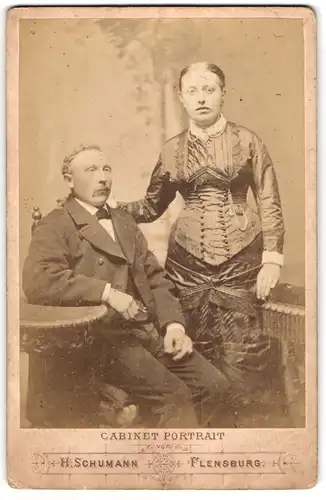 Fotografie H. Schumann, Flensburg, Holm 1, sitzender bürgerlicher Herr mit seiner stehenden Frau