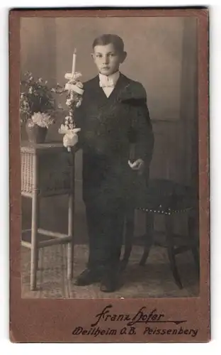 Fotografie Franz Hofer, Weilheim O. B., junger Knabe im Kommunionsanzug mit Kerze