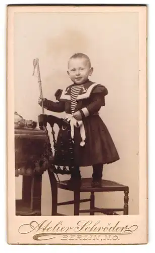 Fotografie A. Schröder, Berlin, Grosse Frankfurter-Str. 117, Kind im Matrosenkleid steht auf Stuhl