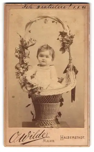 Fotografie O. Wilde, Halberstadt, niedliches Kleinkind sitzt in einer Weidenkorb mit Blumen
