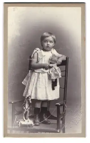 Fotografie Eugen Westendorp, Aachen, niedliches Mädchen mit ihrer Puppe im Arm und Holzpferd