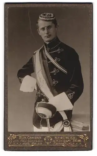 Fotografie Rud. Conrad, Berlin, Portrait Student im vollen Wichs mit Schläger und Biertönnchen