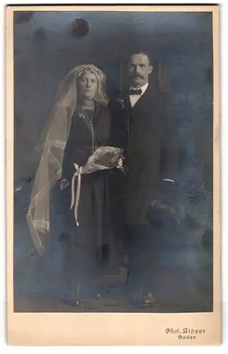Fotografie Zipser, Baden (Schweiz), Ehepaar im schwarzen Kleid mit Schleier und Mann im Anzug mit Zylinder