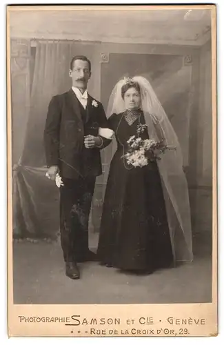 Fotografie Samson & Cie., Geneve, Ehepaar am Hochzeitstag im schwarzen Brautkleid und Anzug mit Schleier, Brautstrauss