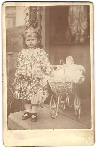 Fotografie unbekannter Fotograf und Ort, niedliches Mädchen im Pünktchenkleid mit ihrer Puppe im Puppenwagen