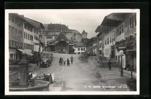 AK Gruyères, Strassenpartie mit Brunnen und Shell-Tankstelle