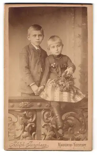 Fotografie Adolph Junghans, Magdeburg-Neustadt, Zwei Geschwisterchen in feinen Kleidern halten Händchen