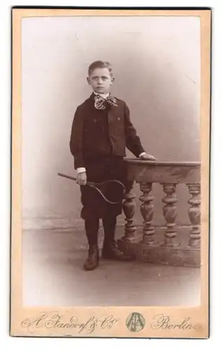 Fotografie A. Jandorf & Co., Berlin, Grosse Frankfurterstr. 113, Hübscher Knabe im Anzug mit Tennisschläger