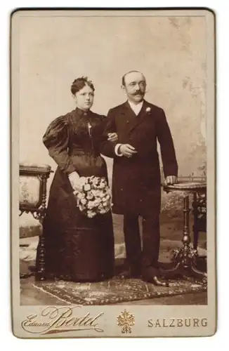 Fotografie Eduard Bertel, Salzburg, Eheleute im schwarzen Brautkleid und Anzug mit Brautstrauss