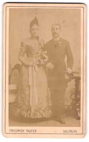 Fotografie Friedrich Taufer, Salzburg, österreichisches Brautpaar im Kleid und im Anzug mit Brautstrauss und Zylinder
