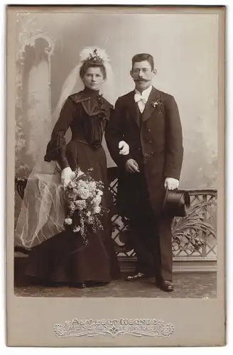 Fotografie Adalbert Werner, München, Hochzeitspaar im schwarzen Brautkleid und Anzug, weisser Schleier und Zylinder
