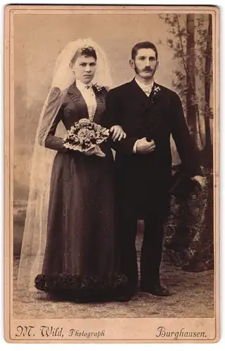 Fotografie M. Wild, Burghausen, Ehepaar im schwarzen Brautkleid und im Anzug mit Zylinder, Koteletten