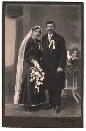 Fotografie Jos. Hinterwimer, Tacherting, Brautpaar im schwarzen Hochzeitskleid und Anzug mit Chapeau Claque
