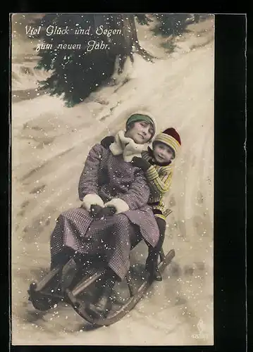 AK Mutter rodelt mit ihrem Sohn den Berg hinunter