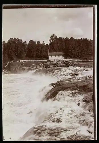 Fotografie M. L. Carstens, Hamburg, Ansicht Kajaani / Finnland, Gebäude am Flussufer neben einem kleinem Wasserfall