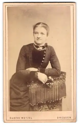 Fotografie Gustav Wetzel, Dresden, Prager Strasse 6, Freundlich blickende junge Dame in einem Kleid mit Samtbesatz