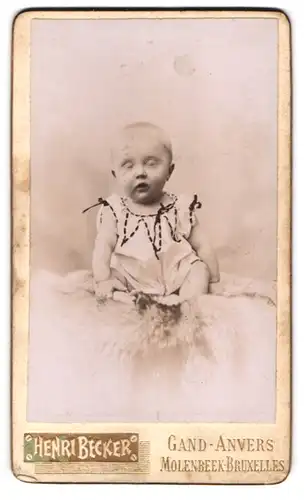 Fotografie Henri Becker, Anvers, 20, Rue des Arquebusiers, Süsses Kleinkind im Hemd sitzt auf einem Fell