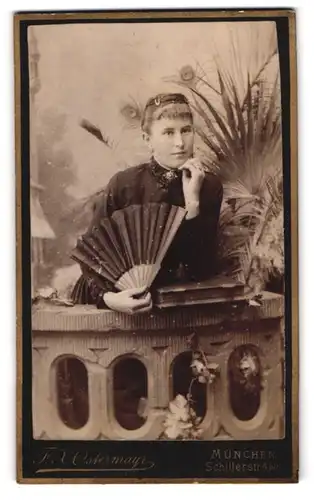 Fotografie F. X. OStermayr, München, junge Dame im dunklen Kleid mit Fächer posiert in einer Studiokulisse