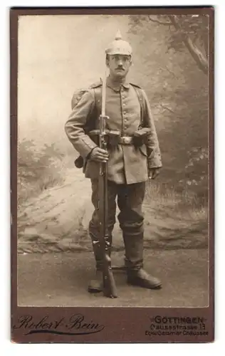 Fotografie Robert Bein, Göttingen, Soldat in Feldgrau Uniform mit Ausmarschgepäck, aufgepflanztes Bajonett, Pickelhaube