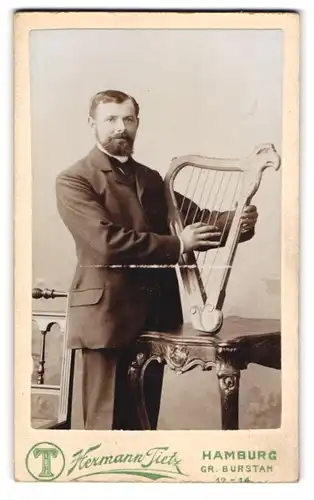 Fotografie Hermann Tietz, Hamburg, Portrait Musiker mit Harfe im Atelier