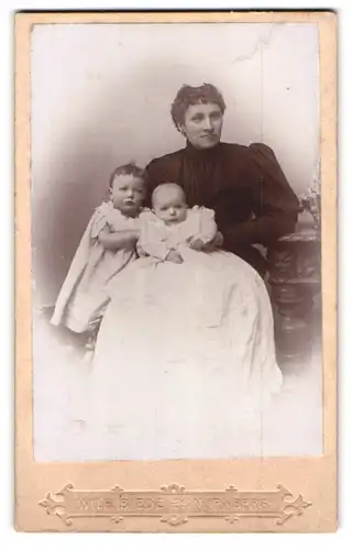 Fotografie Wilh. Biede, Nürnberg, Portrait Mutter mit ihren beiden Kindern im Atelier, Mutterglück