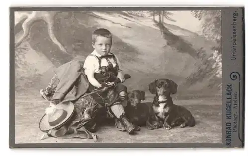 Fotografie Konrad Kugellack, Unterpeissenberg, junger bayrischer Knabe mit seinen zwei Dackel und Flinte im Atelier
