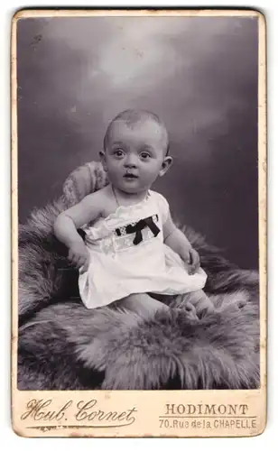 Fotografie Hub. Cornet, Hodimont, 70, Rue de la Chapelle, Süsses Kleinkind im Hemd sitzt auf einem Fell