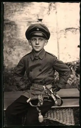 Fotografie 1.WK, Knabe in Uniform mit Offiziersdegen und Schirmmütze