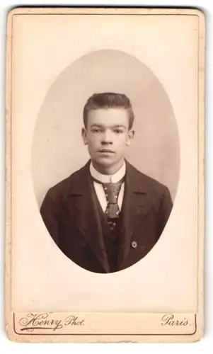 Fotografie Henry, Paris, Rue du Faubourg, Jüngling mit Bürstenfrisur im Dreiteiler mit Krawatte