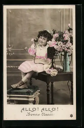 AK Kleines Mädchen sitzt auf einem Tisch und hält den Telefonhörer in der Hand