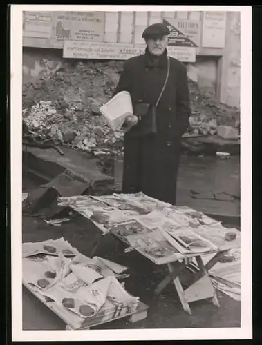 Fotografie unbekannter Fotograf, Ansicht Hamburg, Zeitungshändler an seinem Stand vor Trümmern in der Nachkriegszeit
