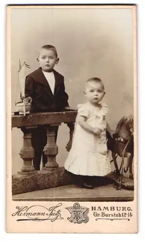 Fotografie Hermann Tietz, Hamburg, zwei kleine Kinder mit Segelschiff und Schauklepferd im Atelier