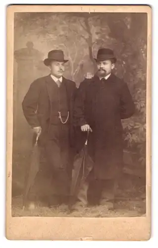 Fotografie unbekannter Fotograf und Ort, zwei Herren in Anzügen mit Melone und Hut samt Schirm